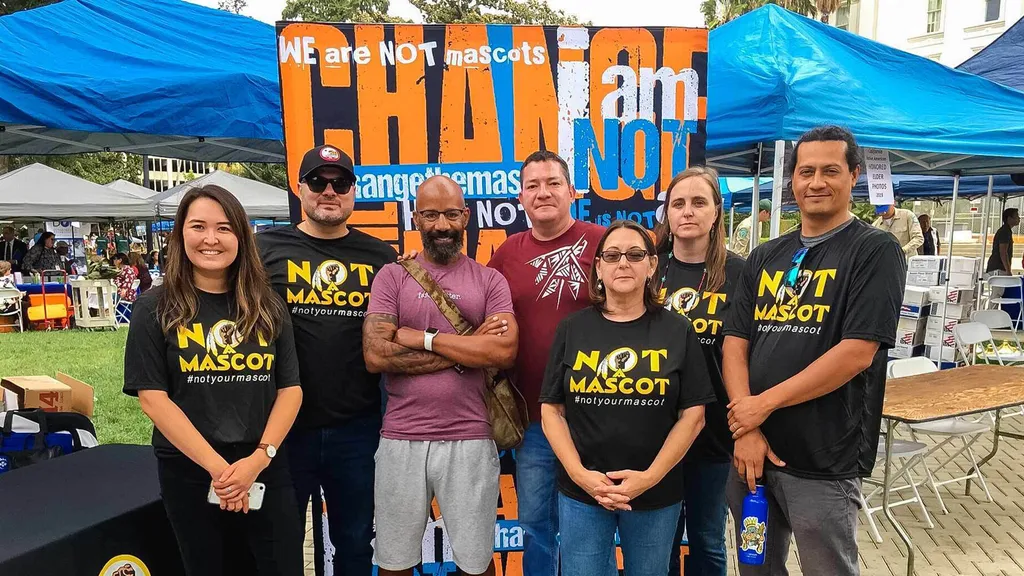 group poses wearing shirts that read, "Not a mascot"