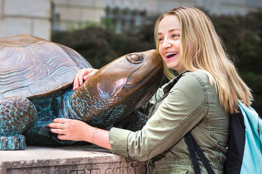 student hugs Testudo statue