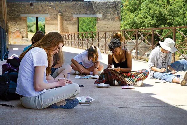 students write while sitting on ground