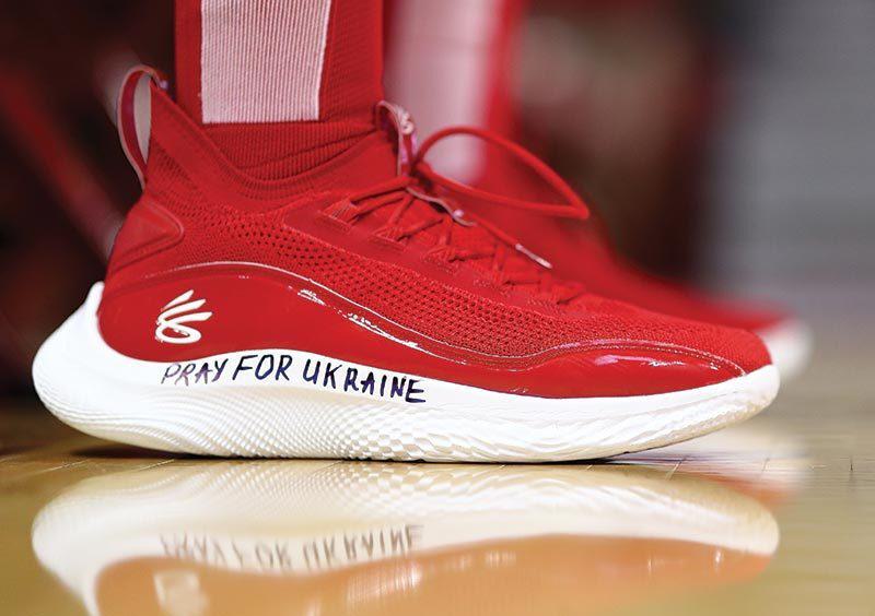 red basketball shoe that reads, "Pray for Ukraine" in black marker