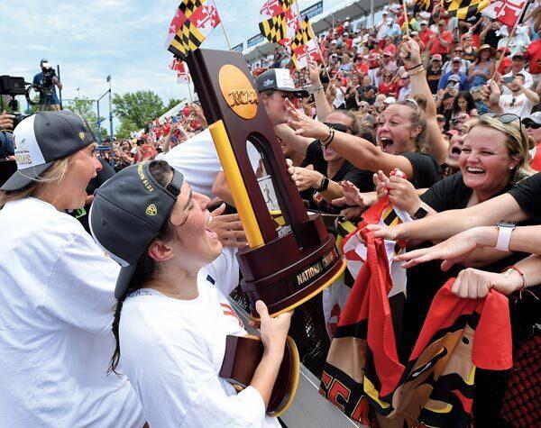 women's lacrosse player hoists trophy