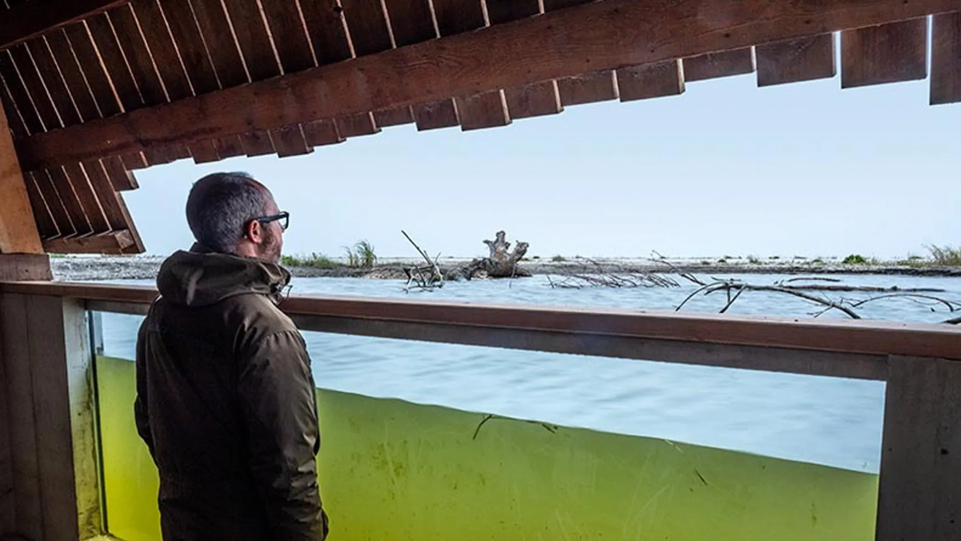 man stands in hide immersed in lake water
