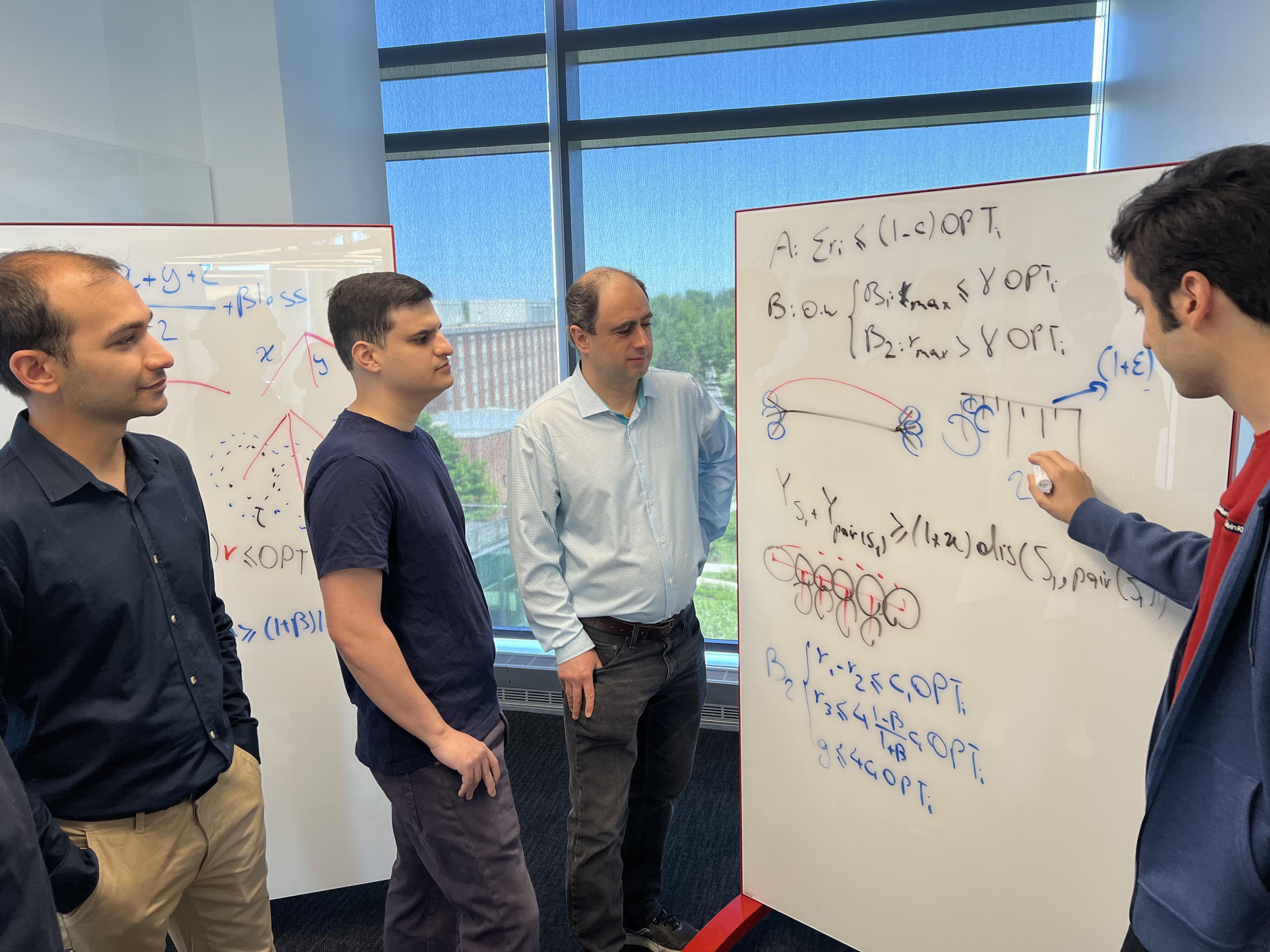 group of four gathers around whiteboard