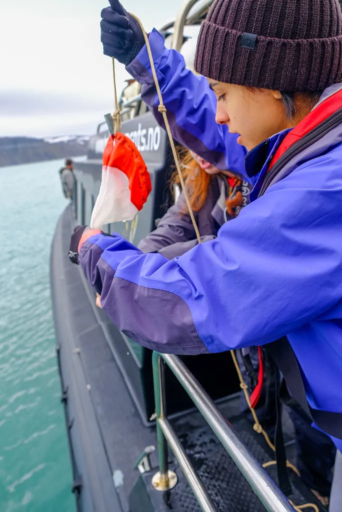 student collects water samples on boat