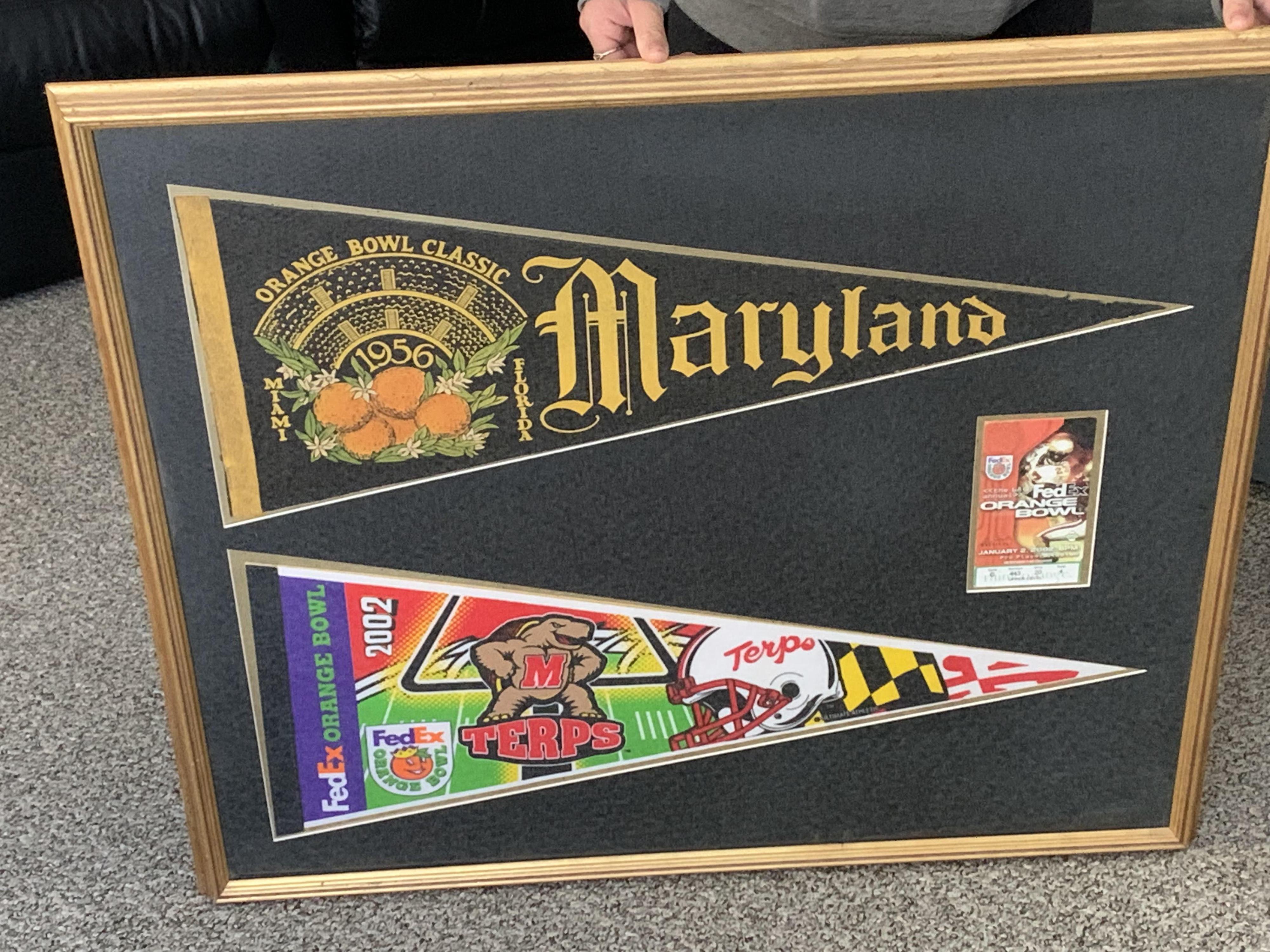 A pennant from the 1956 Orange Bowl that David attended is framed above a pennant from the 2002 Orange Bowl