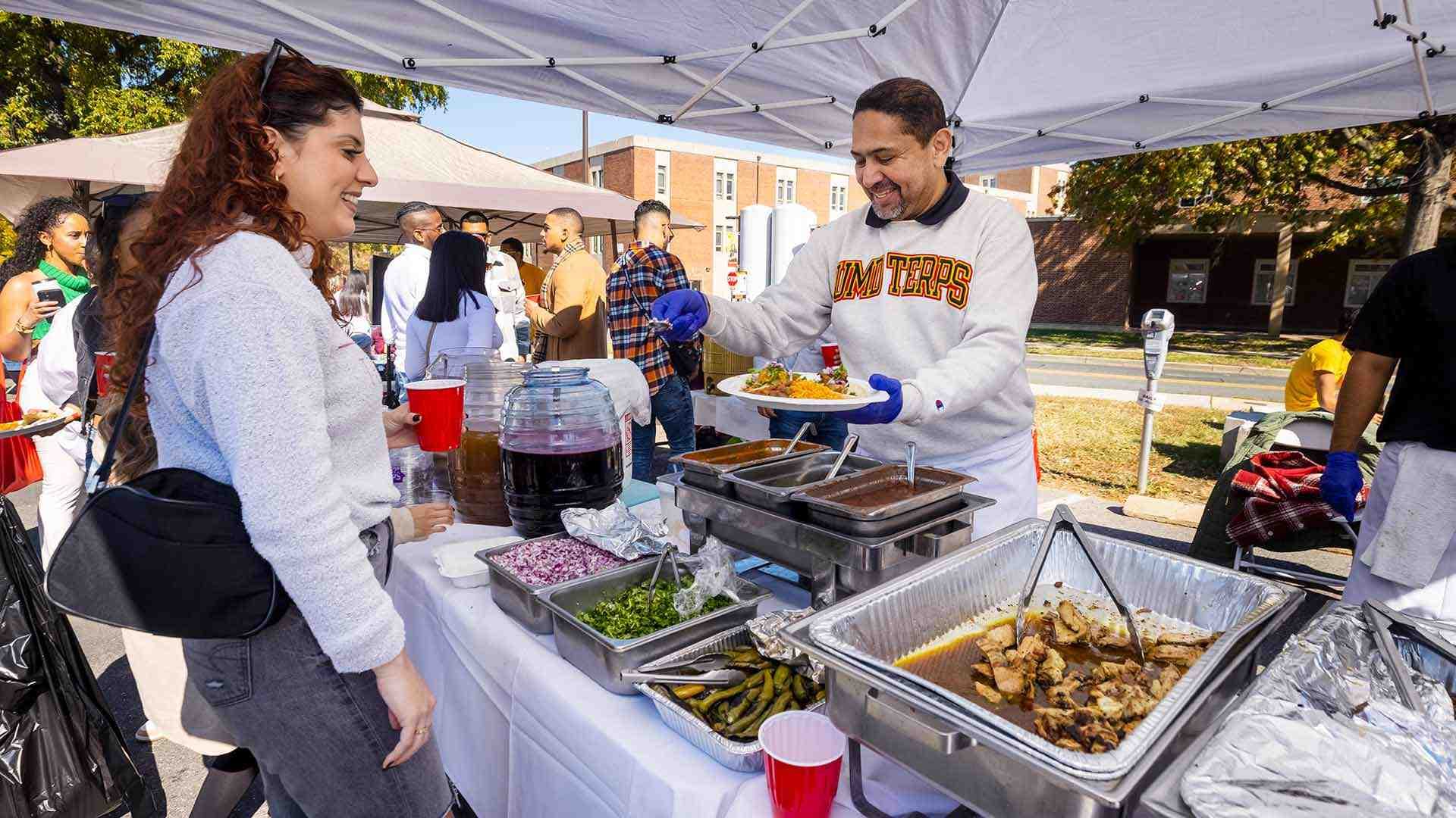 chef serves food at tailgate tent