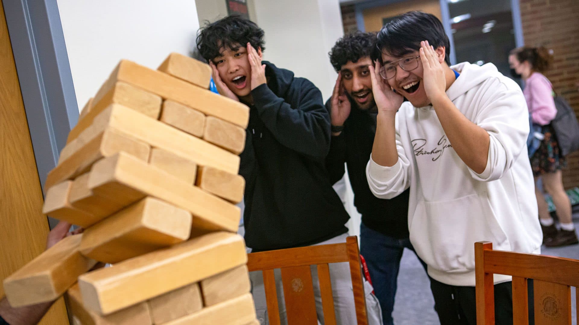 students watch a jenga tower fall and laugh