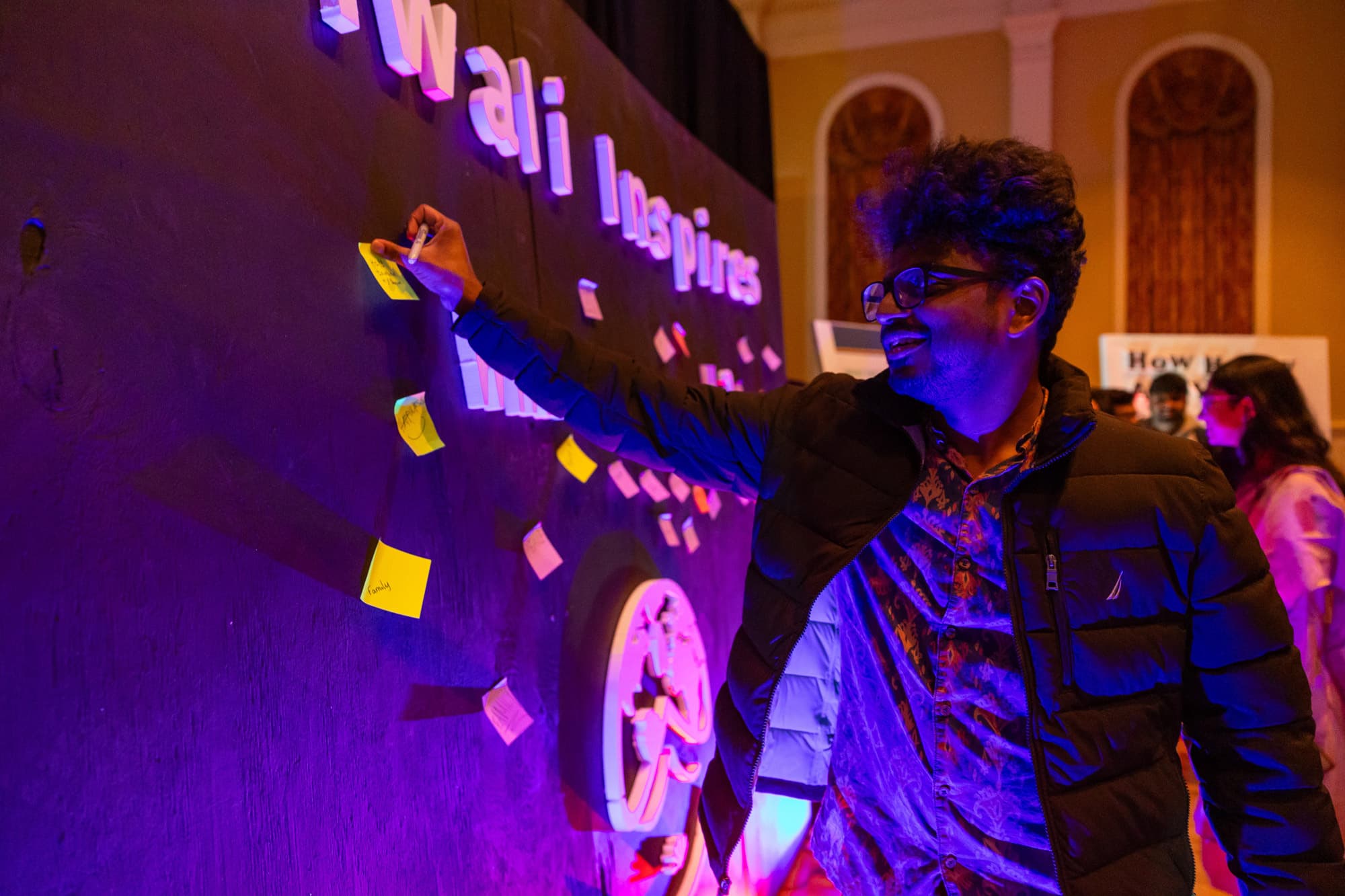 A student adds a post-it note to a wall that says Diwali Inspires