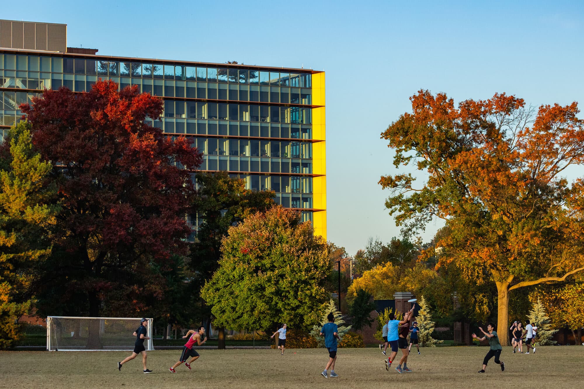 students play frisbee on a field with a building in the background