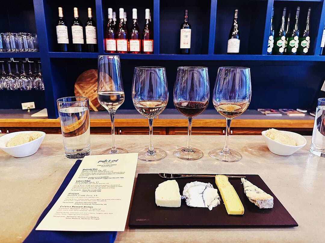 four wines and cheeses lined up at bar