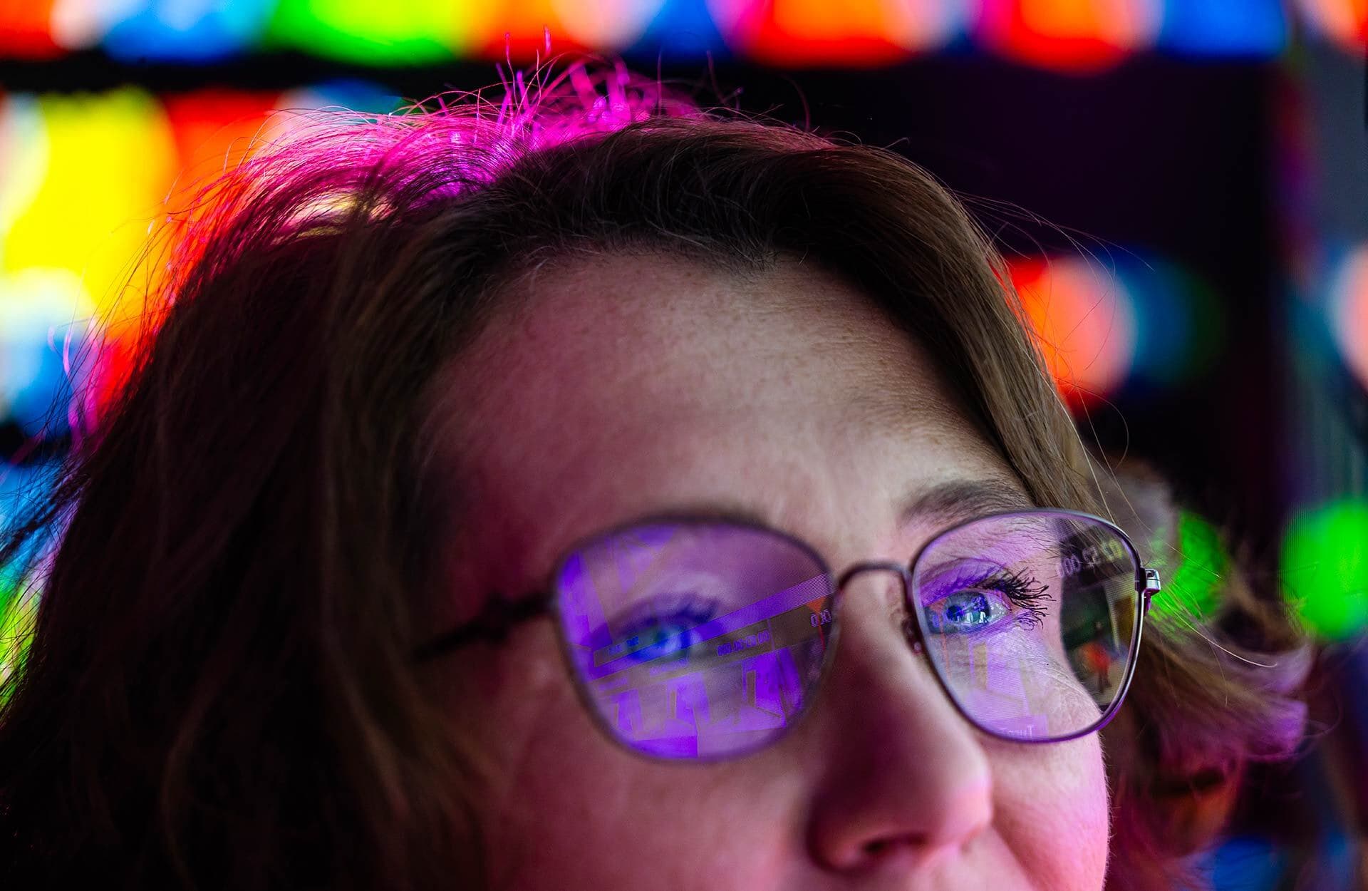 Close-up of a woman's eyes and hair as her glasses have a purple glare