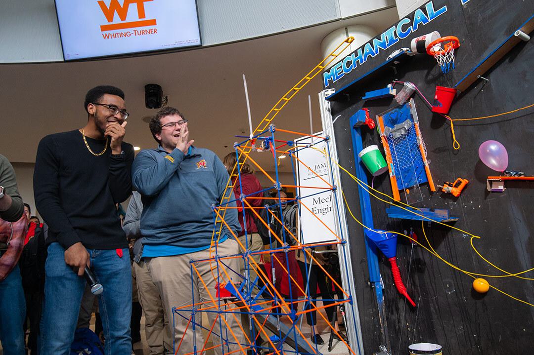 two students laugh looking at their rube goldberg machine