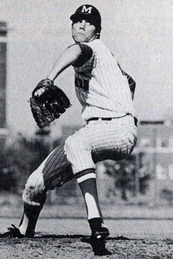 Black and white photo of male baseball pitcher wearing a glove and throwing a ball