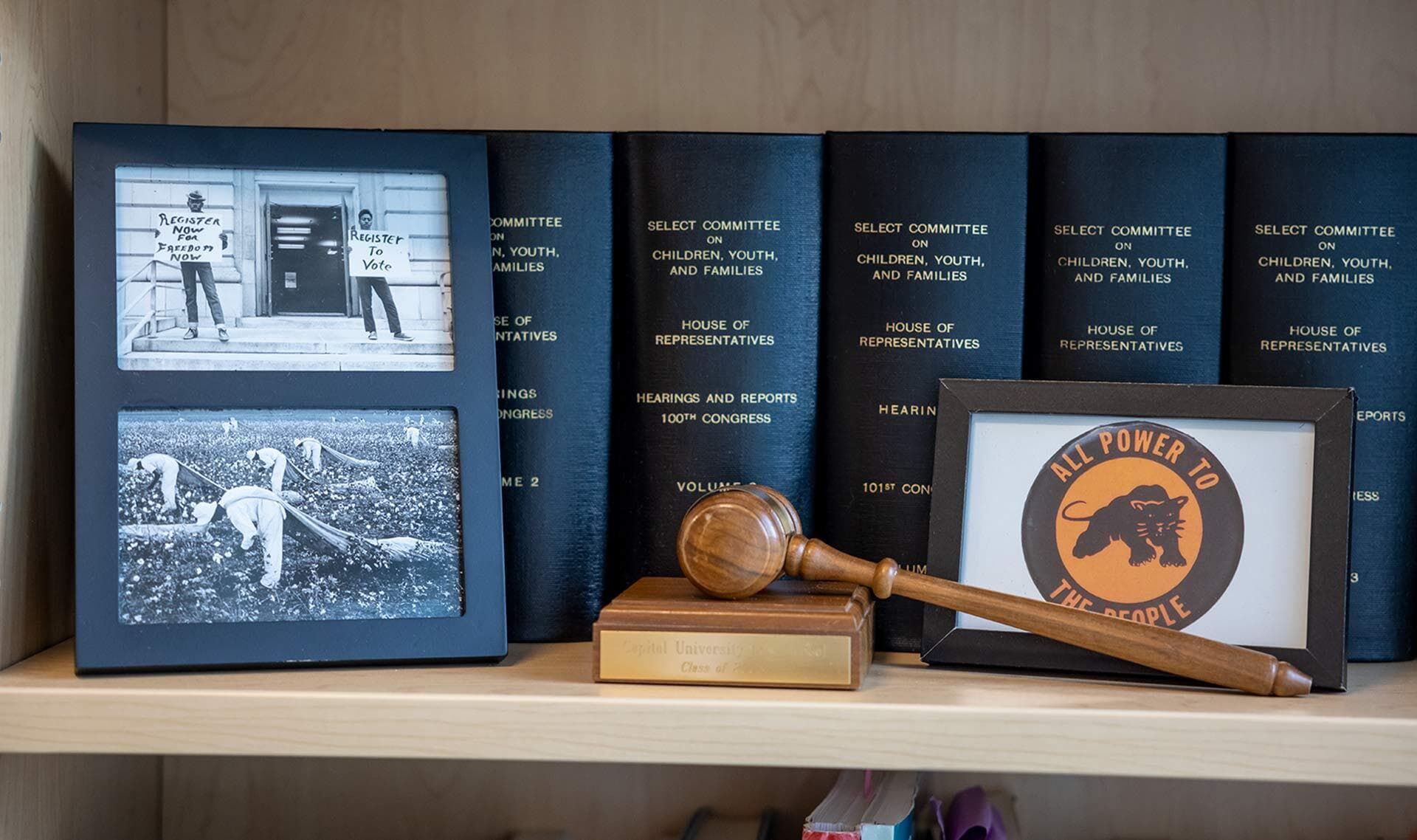 Framed black and white photos, thick black tomes of Congressional records, a wooden gavel and a postcard that says "All Power to the People"