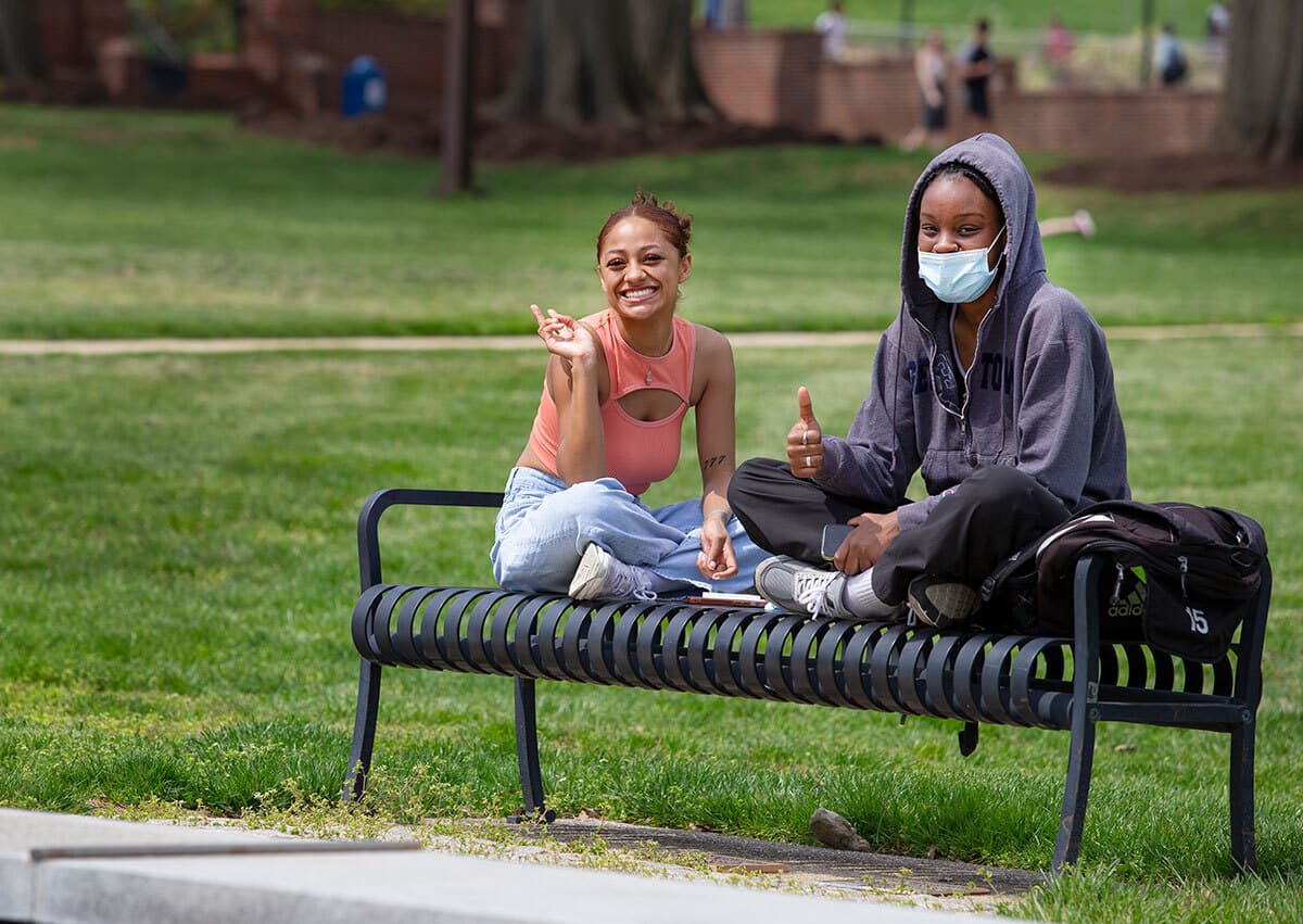 Two students sit on bench on McKeldin Mall