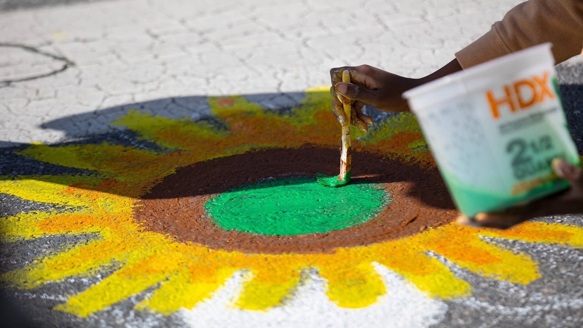a person's hand is shown painting a sunflower on the street