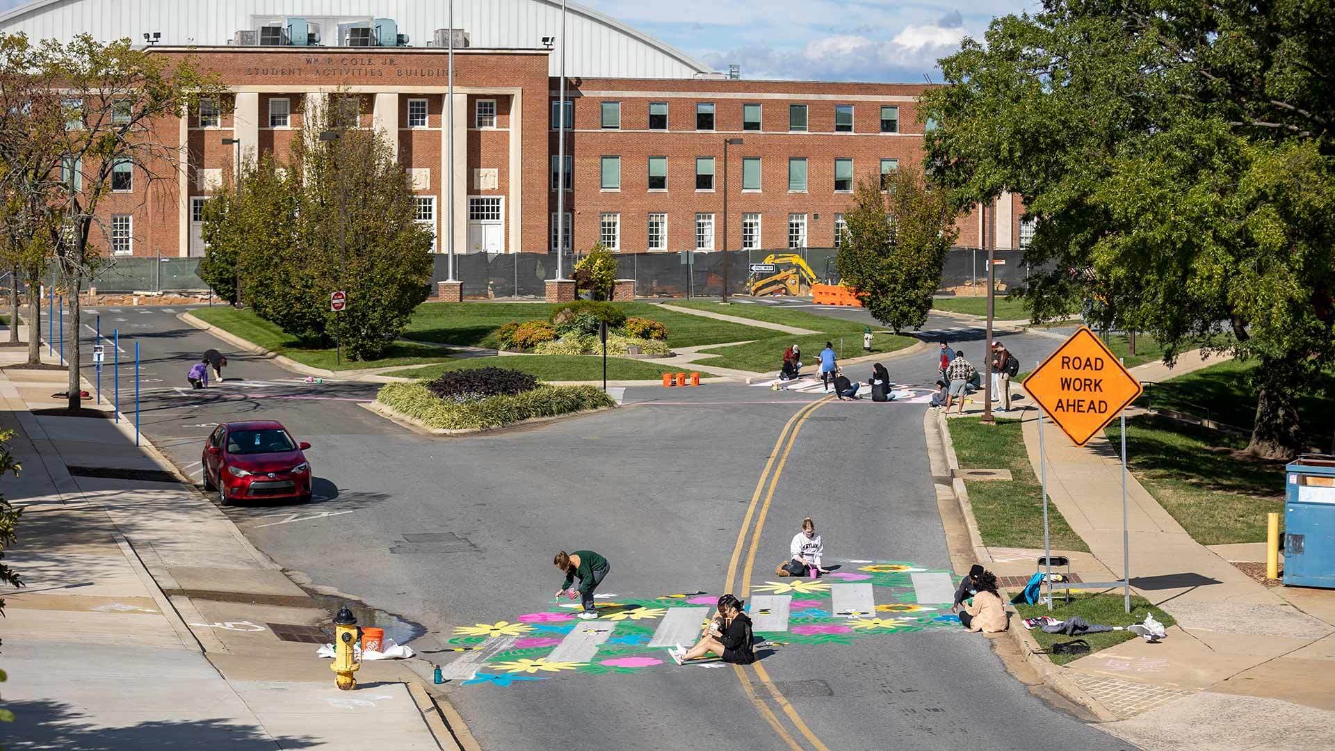 overview from a high vantage of many studients painting three crosswalks near Cole Field House