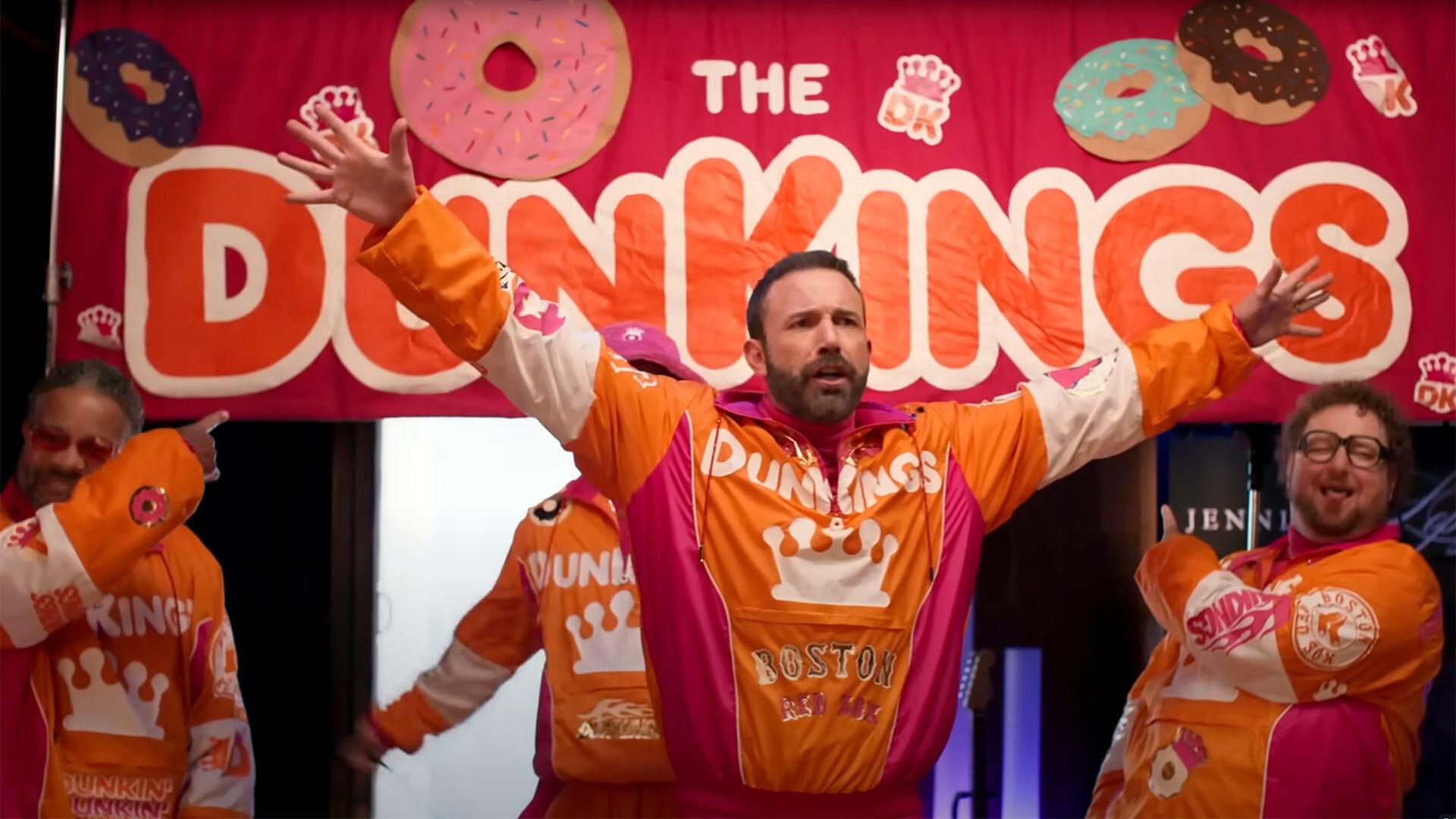 Ben Affleck with arms wide open in front of a DunKings sign