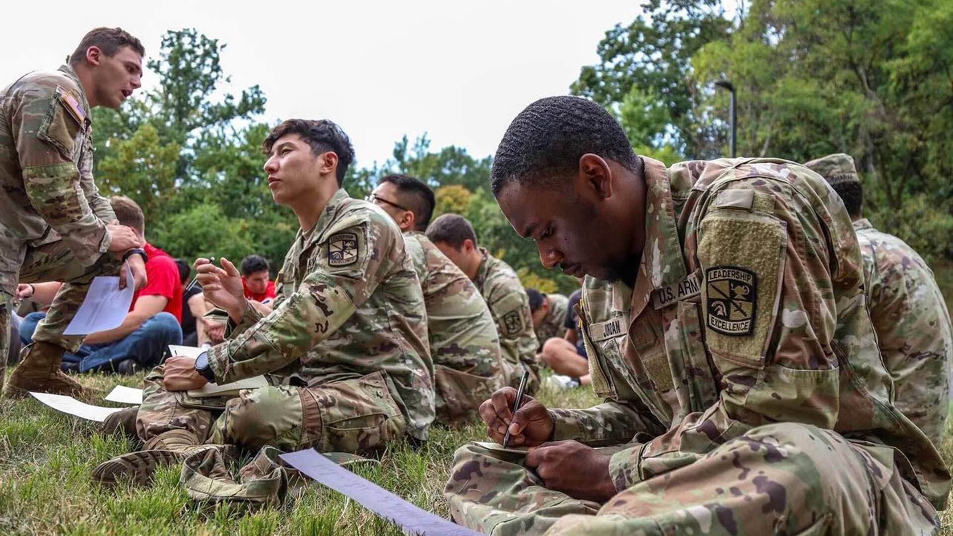 uniformed cadets taking notes in the grass