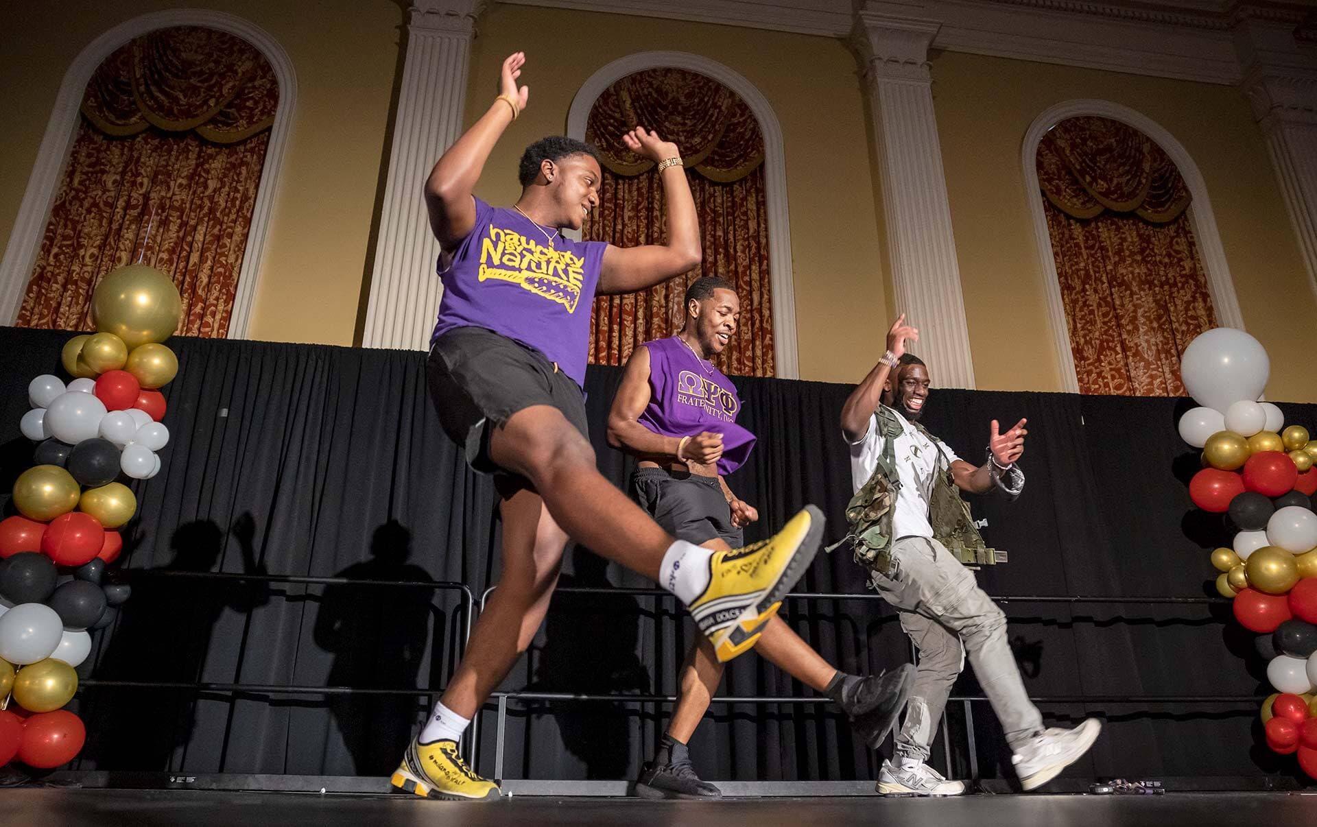 three students dance on stage