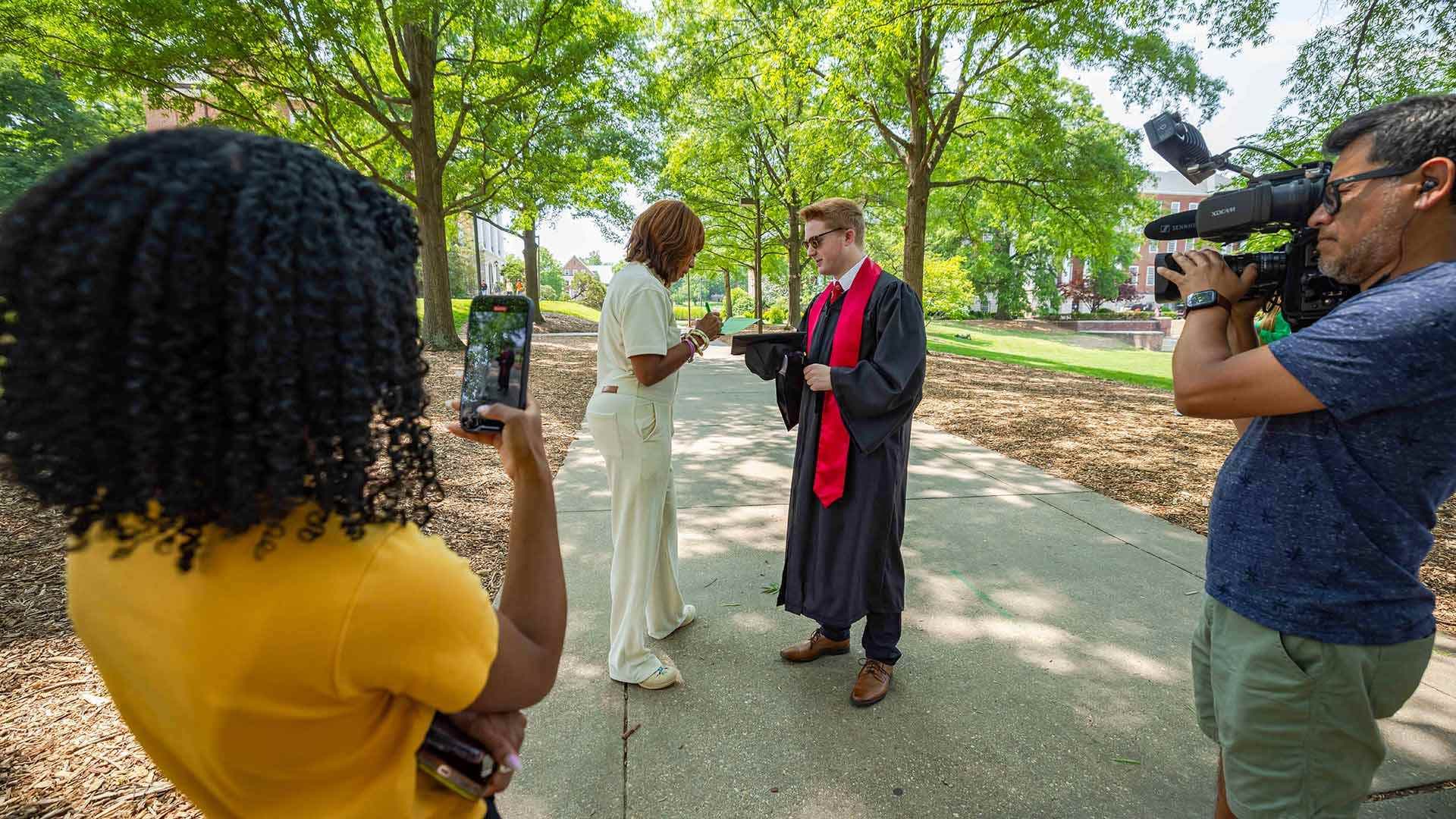 Gayle King talks to a student, who is wearing graduation regalia