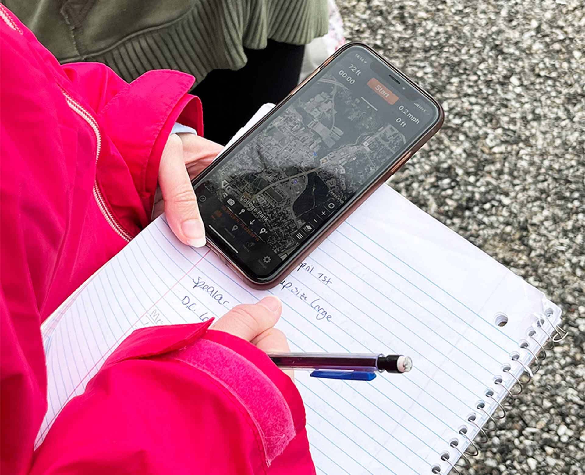 closeup of hands holding phone and taking notes in notebook