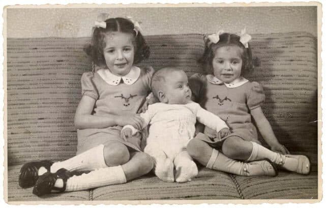 two sisters hold baby