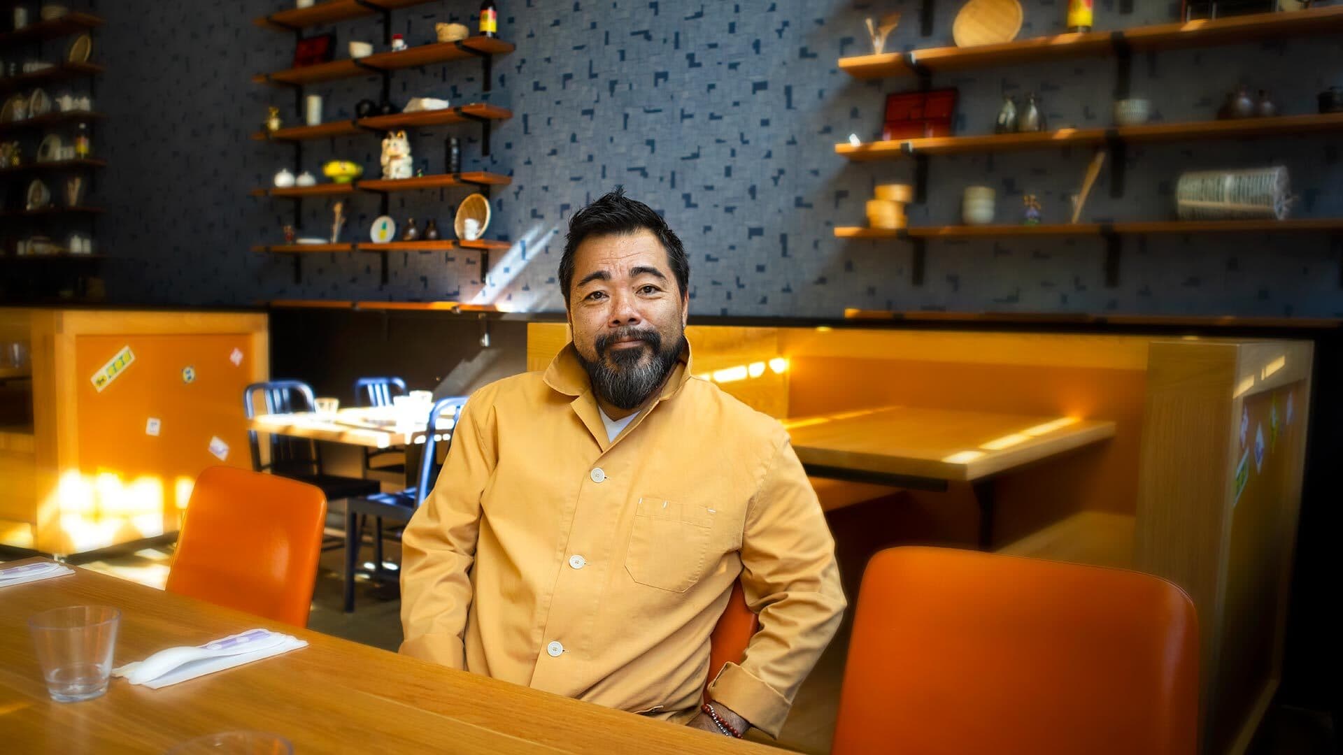 Katsuya Fukushima sitting in a yellow jacket inside his restaurant Hatoba