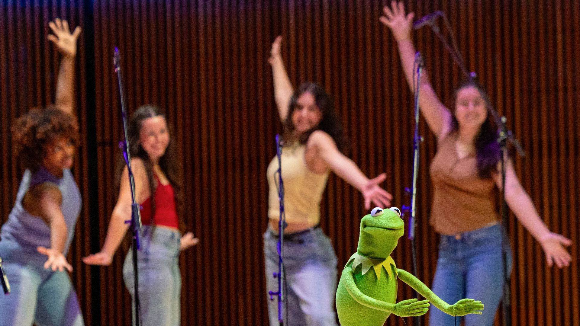 kermit sings in front of four female dancers