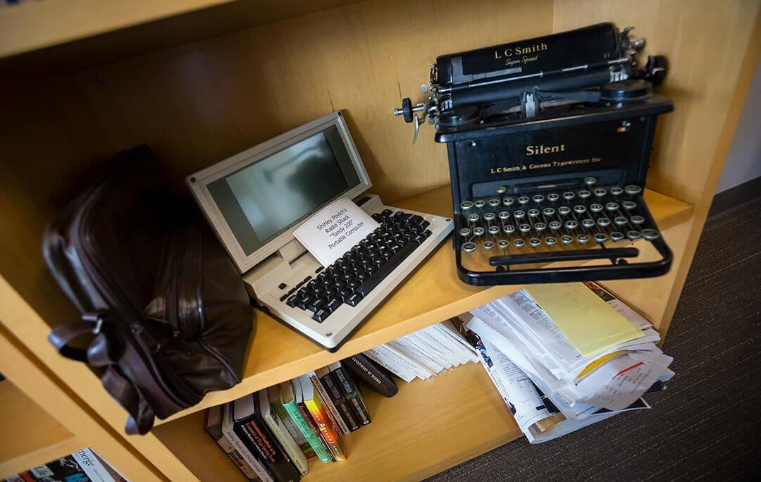Laptop and typewriter on a shelf