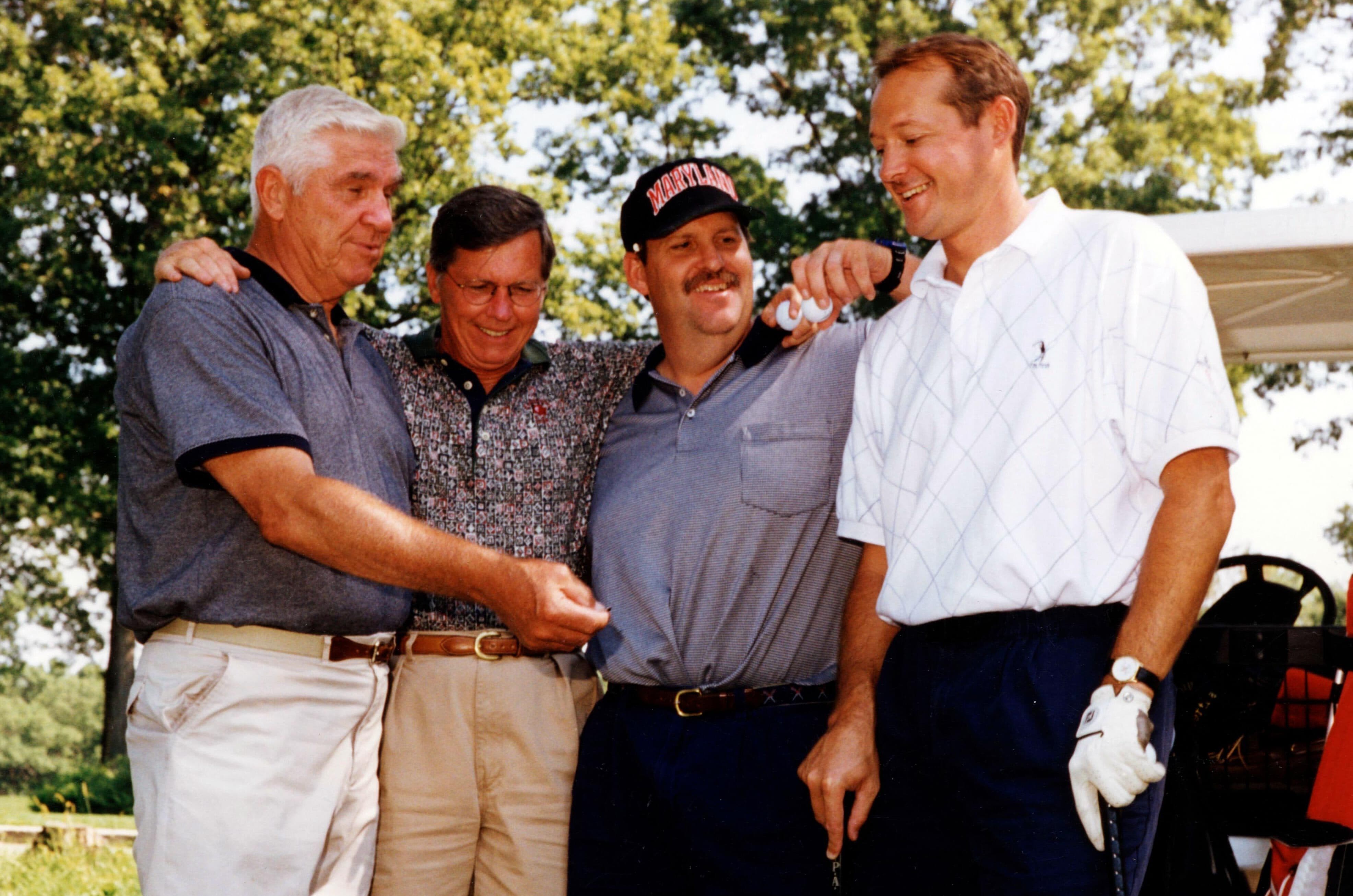 group of four men at a golf tournament
