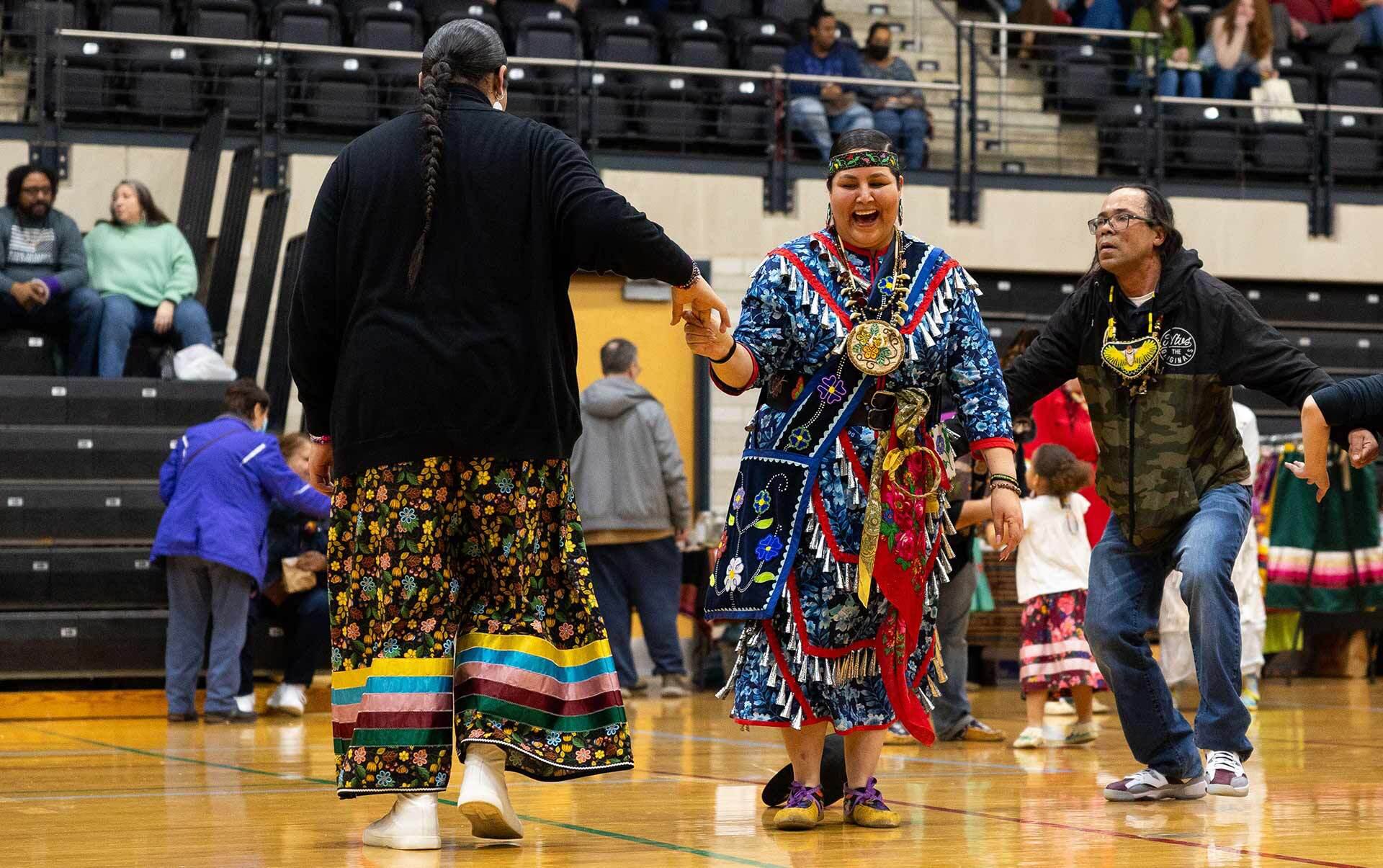 two dancer in native attire hold hands and dance