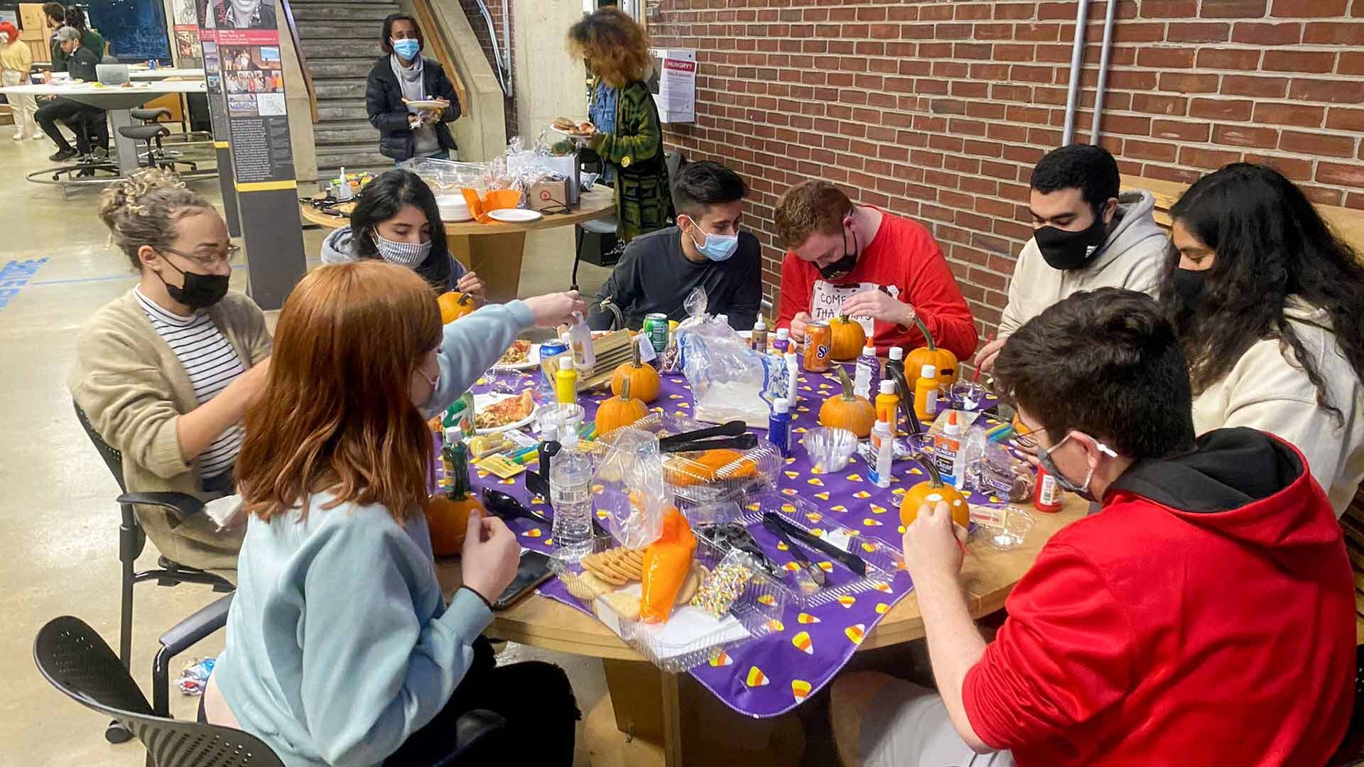 Students paint pumpkins at Halloween party