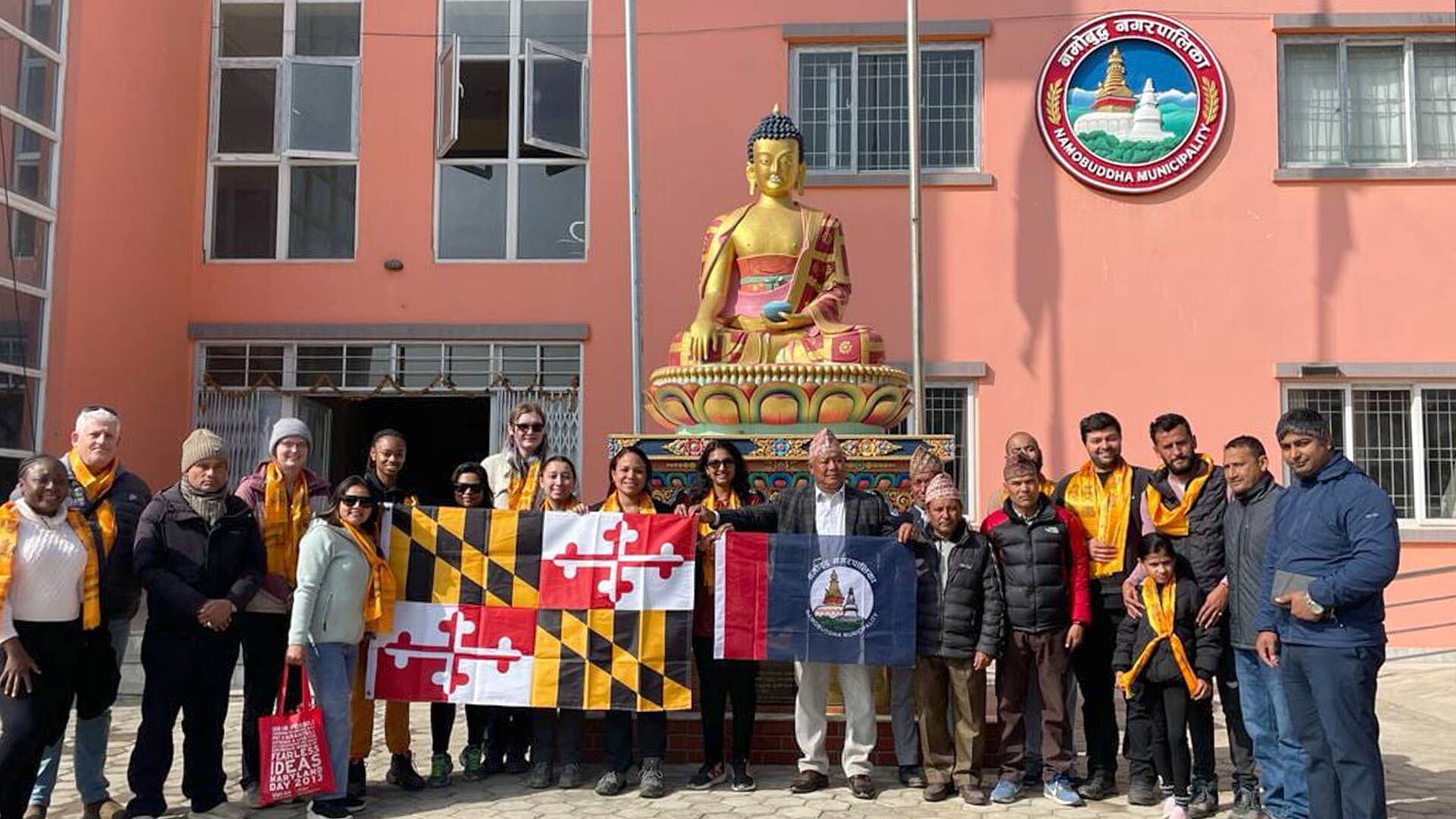 group holding Maryland flag poses with Namobuddha Mayor Kunsang Lama and his staff outside of the Municipality office