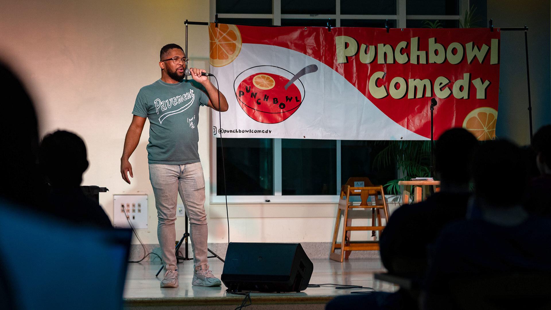A man performs stand-up comedy on a stage