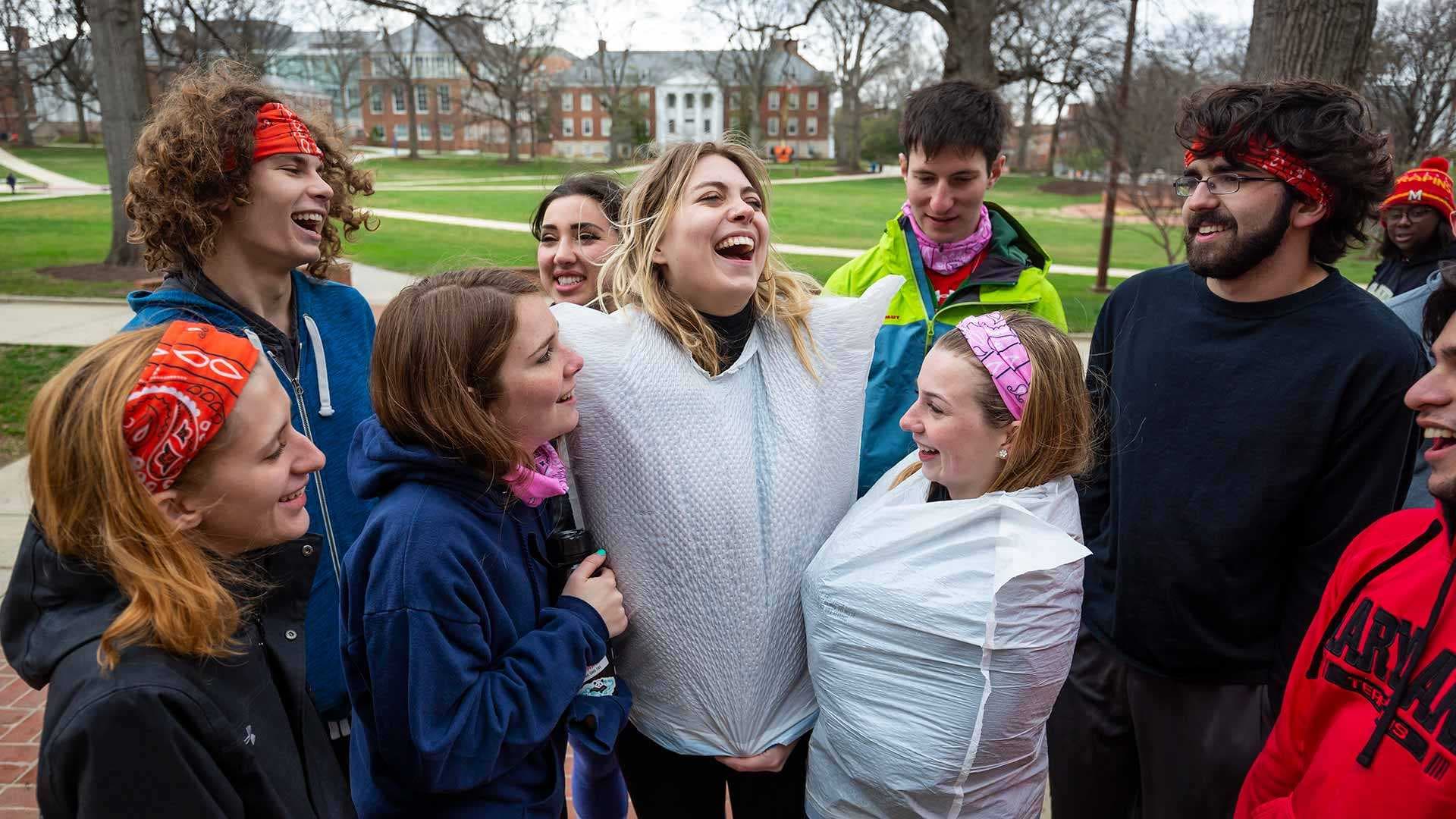 students wearing bandanas and trash bags laugh on McKeldin Mall