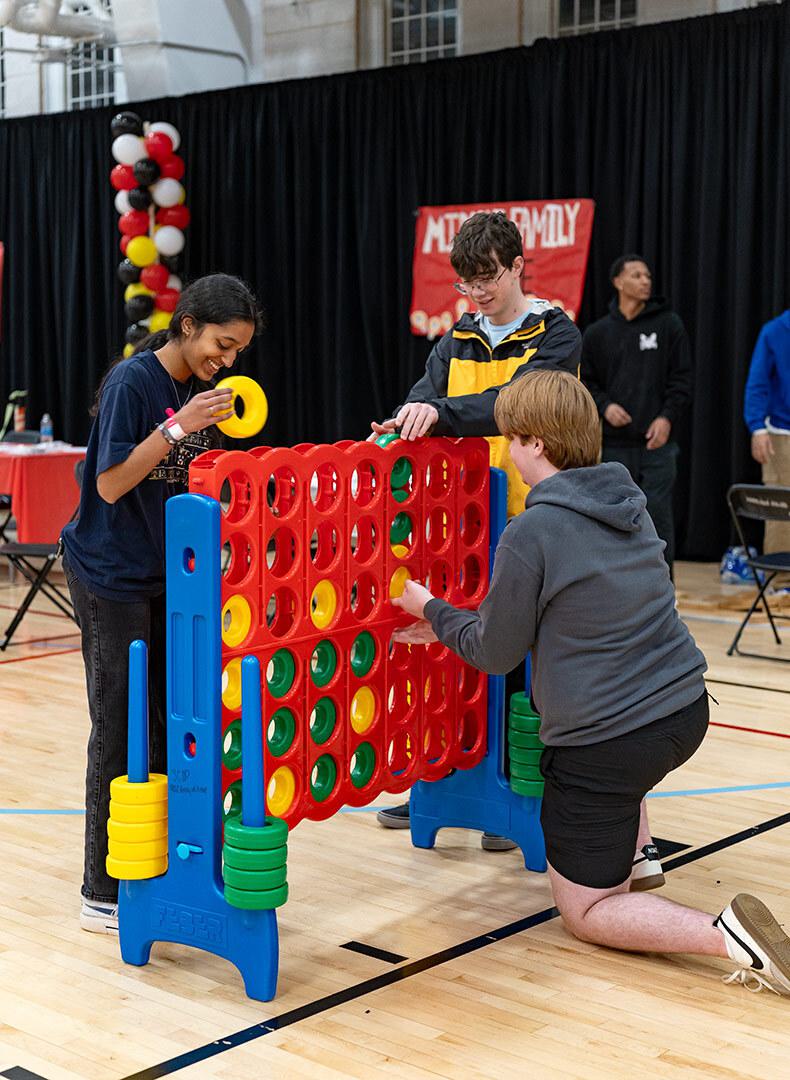 three people play life-size Connect 4, the game