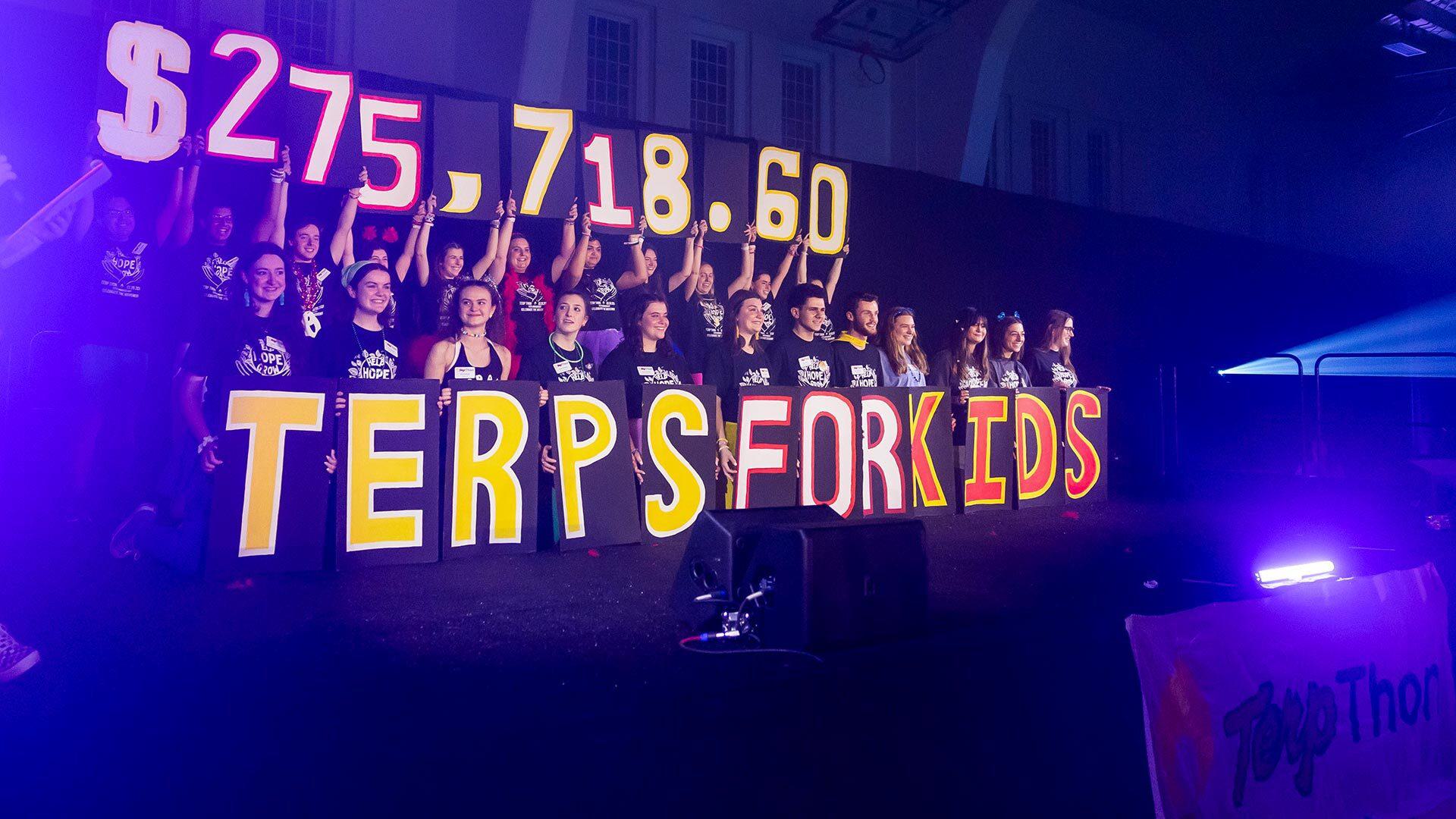 multiple folks hold up a big number and world "terps for kids" on a stage