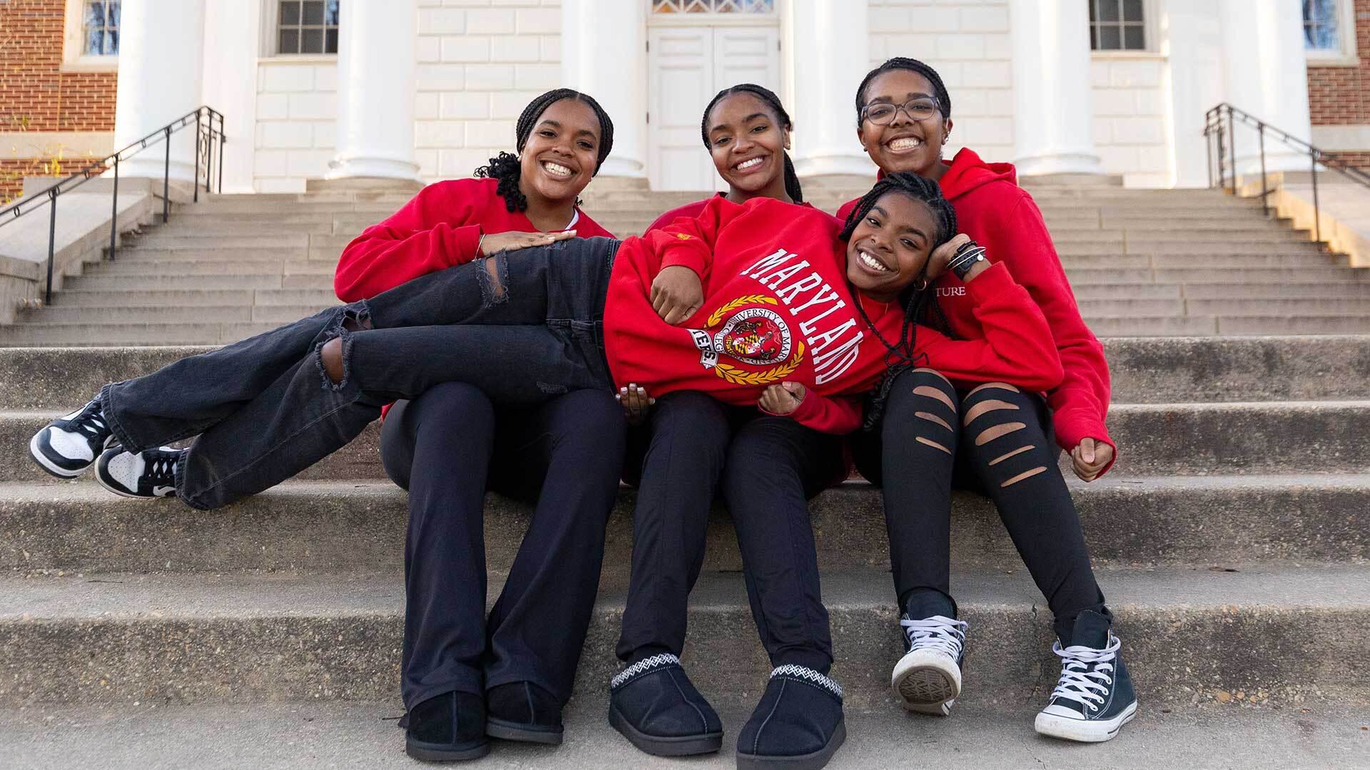 One Edwards sister lays across the other three sisters' laps, all wearing red Terps gear