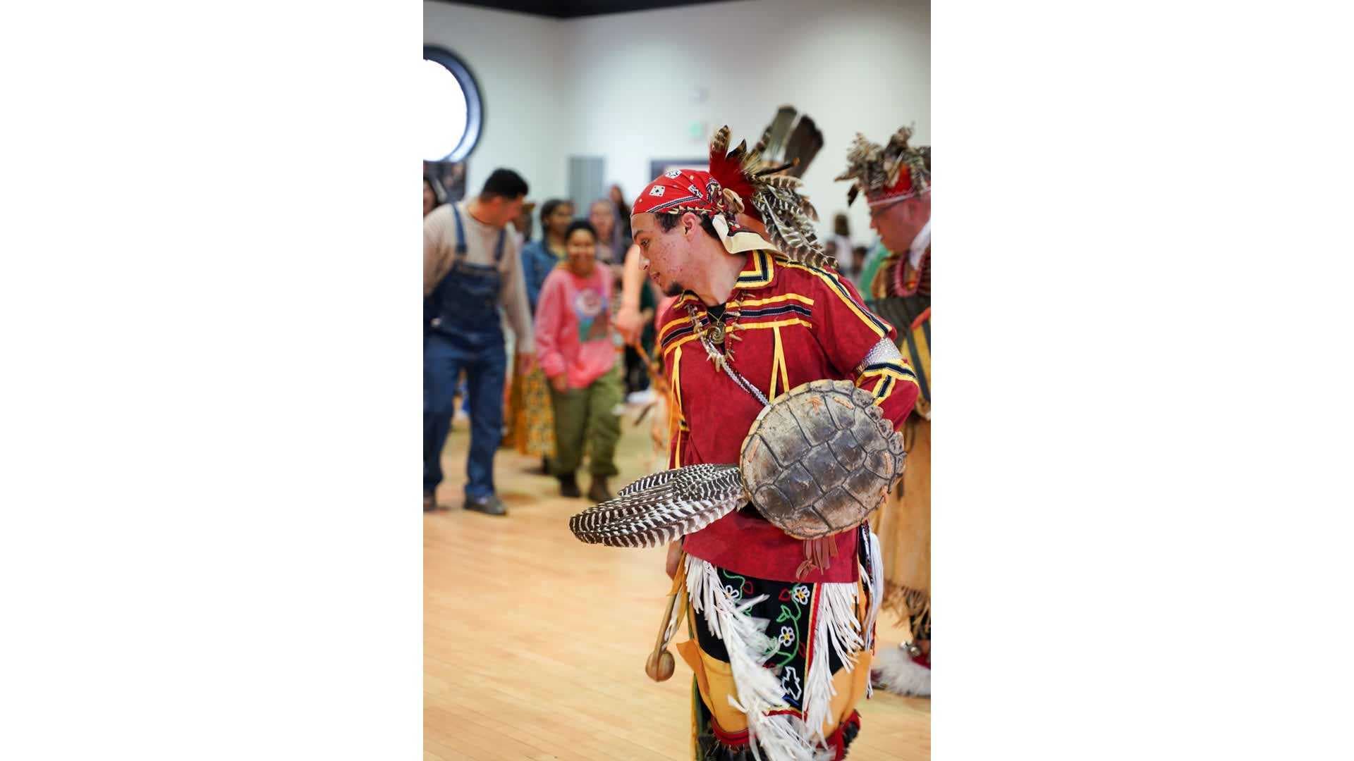 Native American with turtle shell and feathers at Pow Wow
