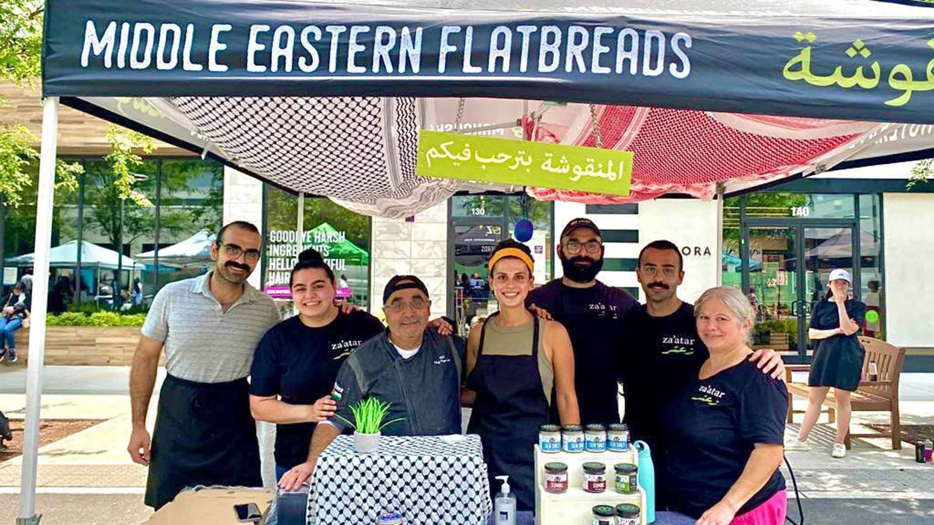 Dubbaneh family at a farmers market with tent that says, "Middle Eastern Flatbreads"