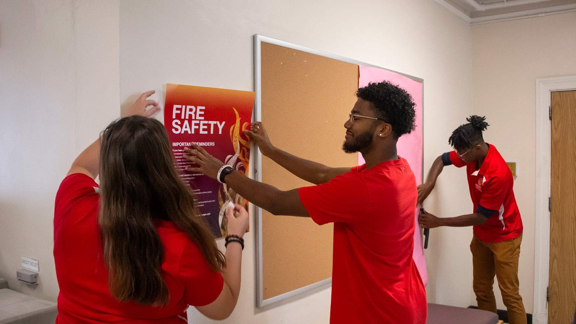 Resident assistants hang fire safety poster