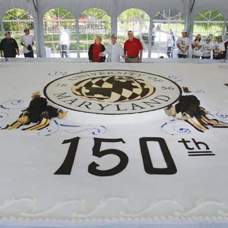 giant cake with UMD seal and "150th" written in icing