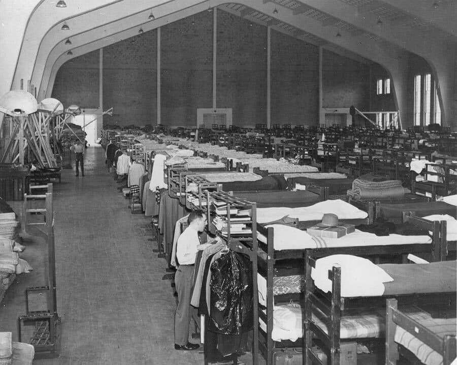 A student hangs clothes amid the rows of bunk beds in the Armory