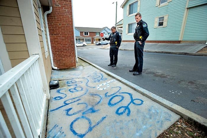 police officers look at blue writing on sidewalk