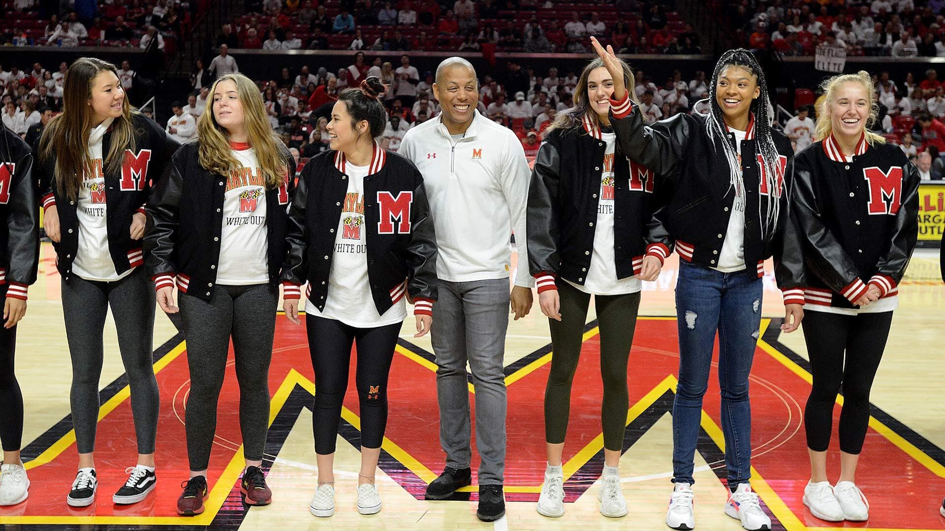 women's basketball players standing with Damond Evans in the center