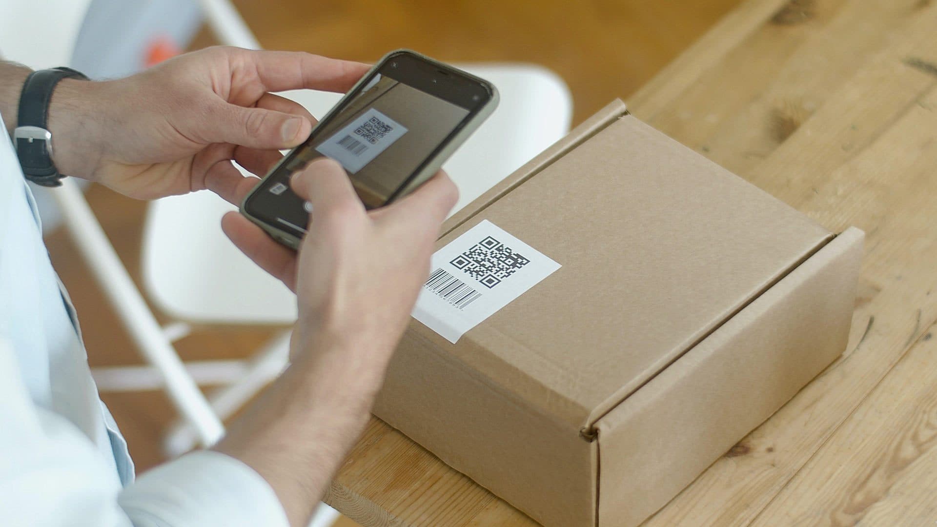 Person uses their smartphone to scan a QR code on a package