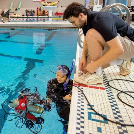 student controls underwater robot in pool