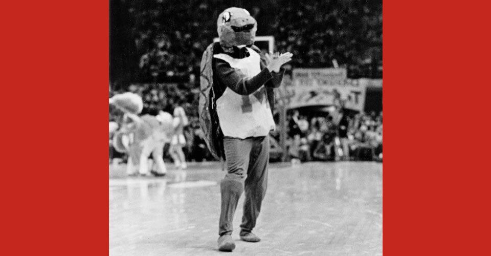 old version of Testudo mascot claps on basketball court